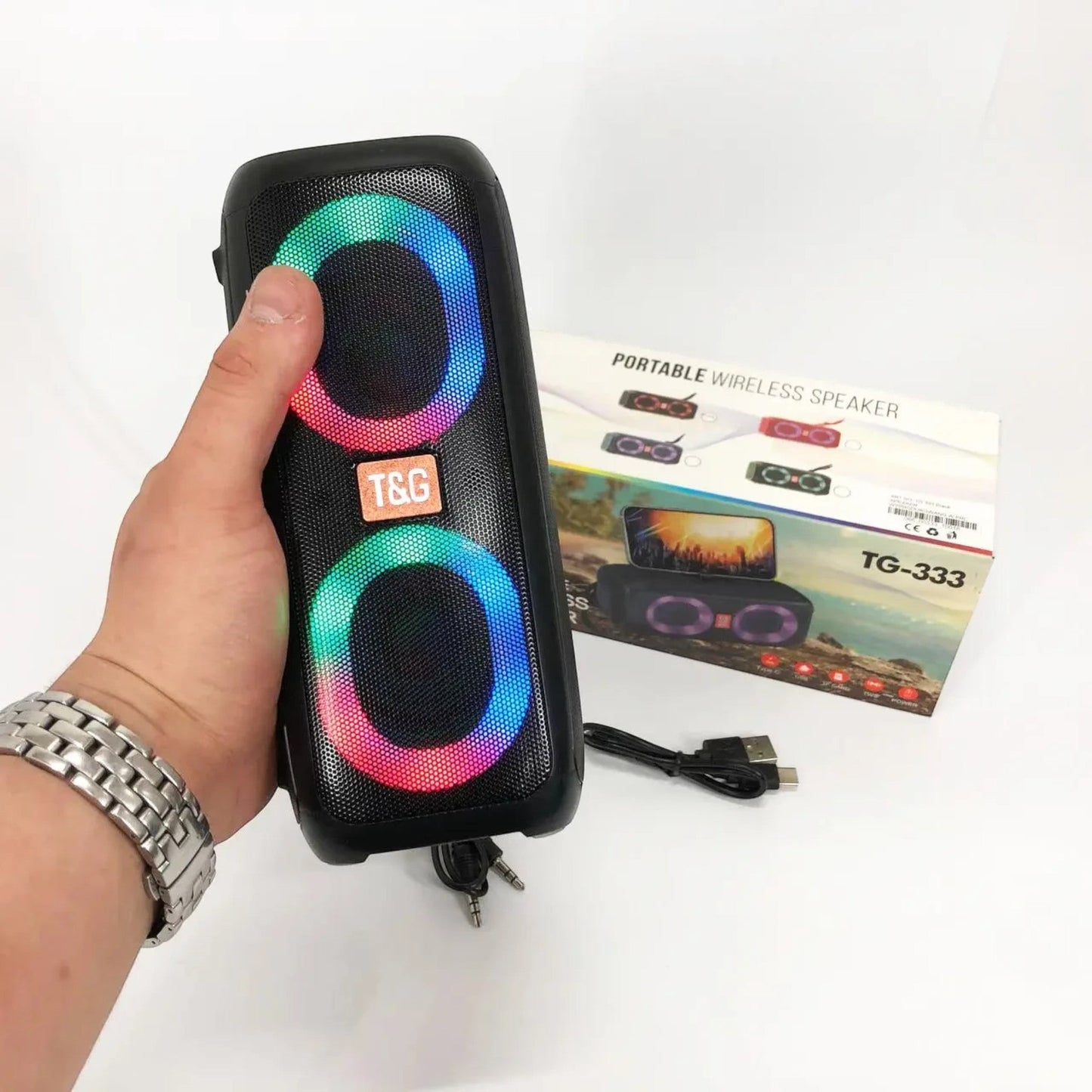 Parlante T&G TG-333 negro sostenido en la mano con luces RGB encendidas